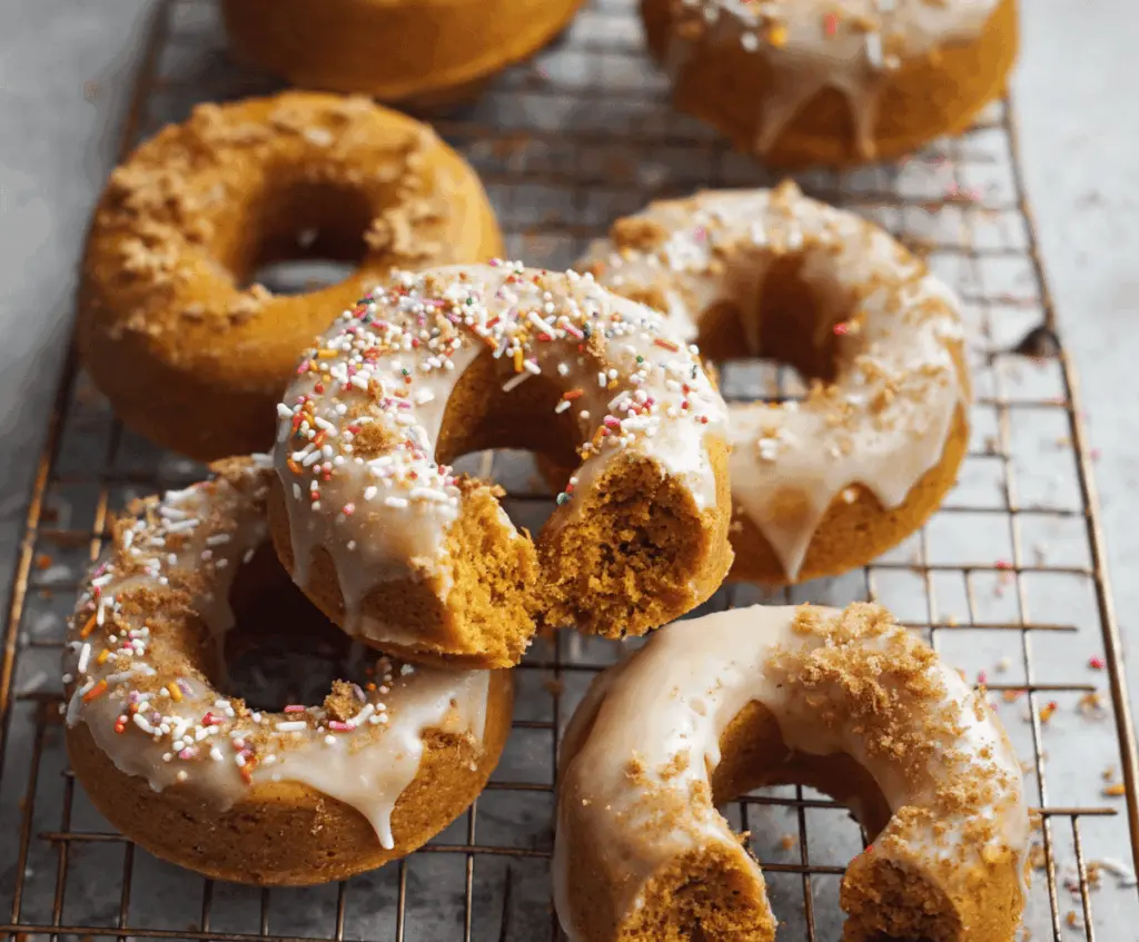 Delicious baked pumpkin donuts topped with cinnamon and glaze on a rustic plate, perfect for fall treats