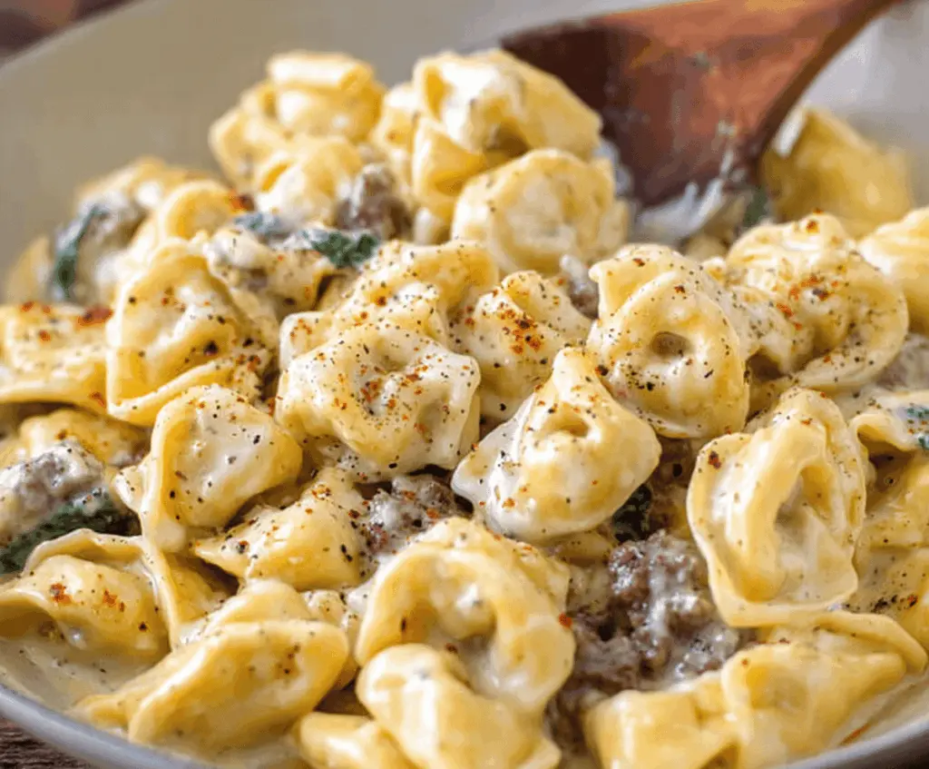 Creamy garlic butter beef and spinach tortellini served on a white plate, garnished with fresh herbs, perfect for a flavorful Italian-inspired meal.