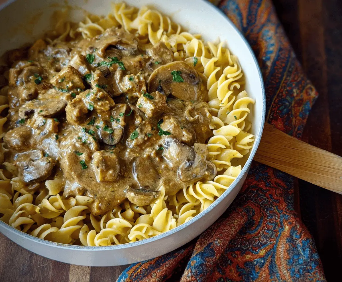 Creamy mushroom and seitan stroganoff served over noodles, featuring sautéed mushrooms, seitan strips, and a savory sauce in a bowl.