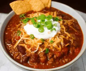 Delicious homemade Texas Roadhouse Chili with optional beans in a rustic bowl, garnished with shredded cheese and fresh herbs, perfect for hearty comfort food.