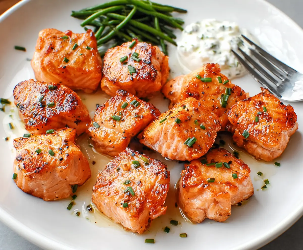 Delicious salmon bites served on a plate, garnished with lemon and herbs, perfect for a quick and flavorful meal.