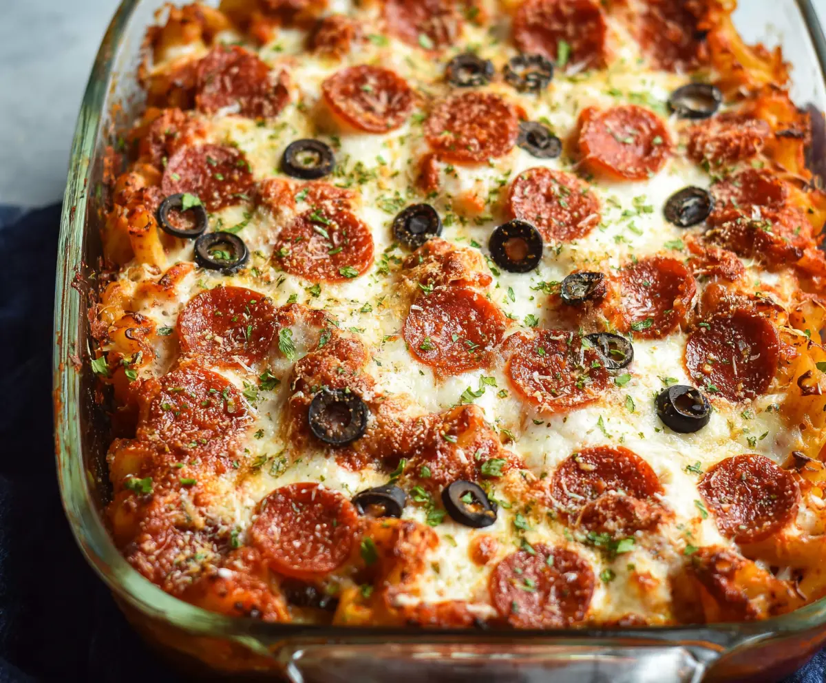 Delicious Easy Weeknight Pizza Casserole with melted cheese, tomatoes, and pepperoni topped in a baking dish.